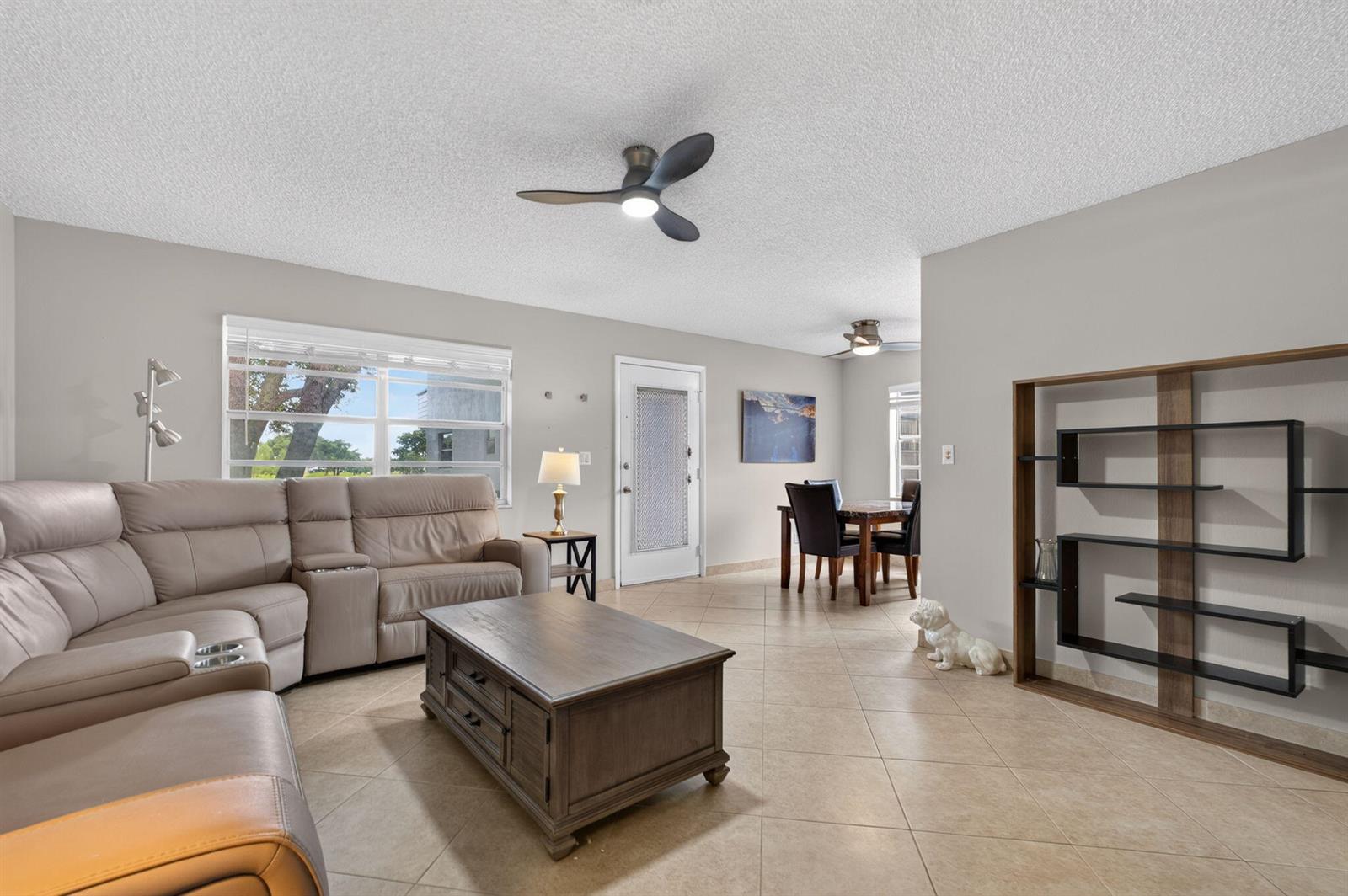 A living room with tile floors, a sectional sofa, a coffee table, and a bookshelf — 942 Normandy T Trail # 942, Delray Beach FL 33484, DELRAY BEACH, FL