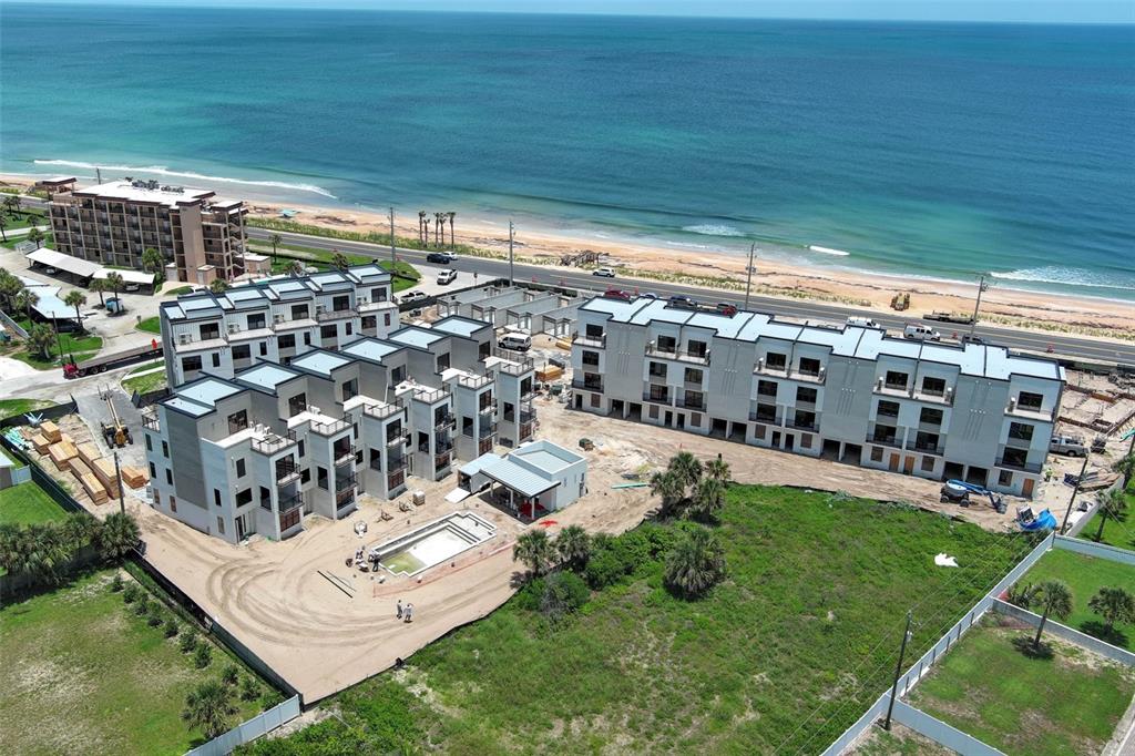 An aerial view shows a multi-story residential complex under construction near a beach — 2360 OCEAN SHORE BOULEVARD UNIT 30, ORMOND BEACH, FL