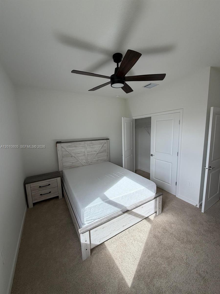 A bedroom features a white bed frame, a matching nightstand, and a ceiling fan — 132 NE 13th Cir, Homestead FL 33033, HOMESTEAD, FL