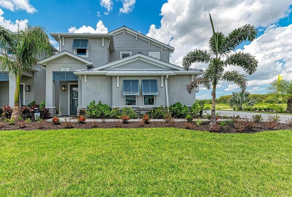 A two-story gray stucco house features a front porch, palm trees, and a green lawn — 10016 REMBRANDT WAY UNIT 101, BRADENTON, FL