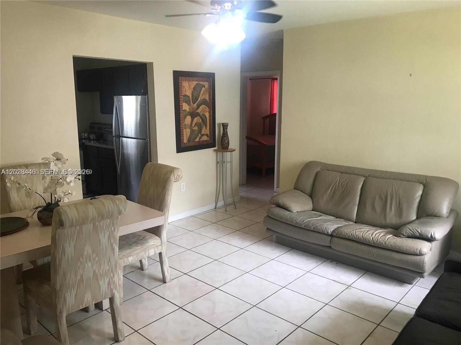 A dining area and living room feature tile floors, a tan sofa, and a ceiling fan — 133 NW 57th St # 2, Miami FL 33127, MIAMI, FL