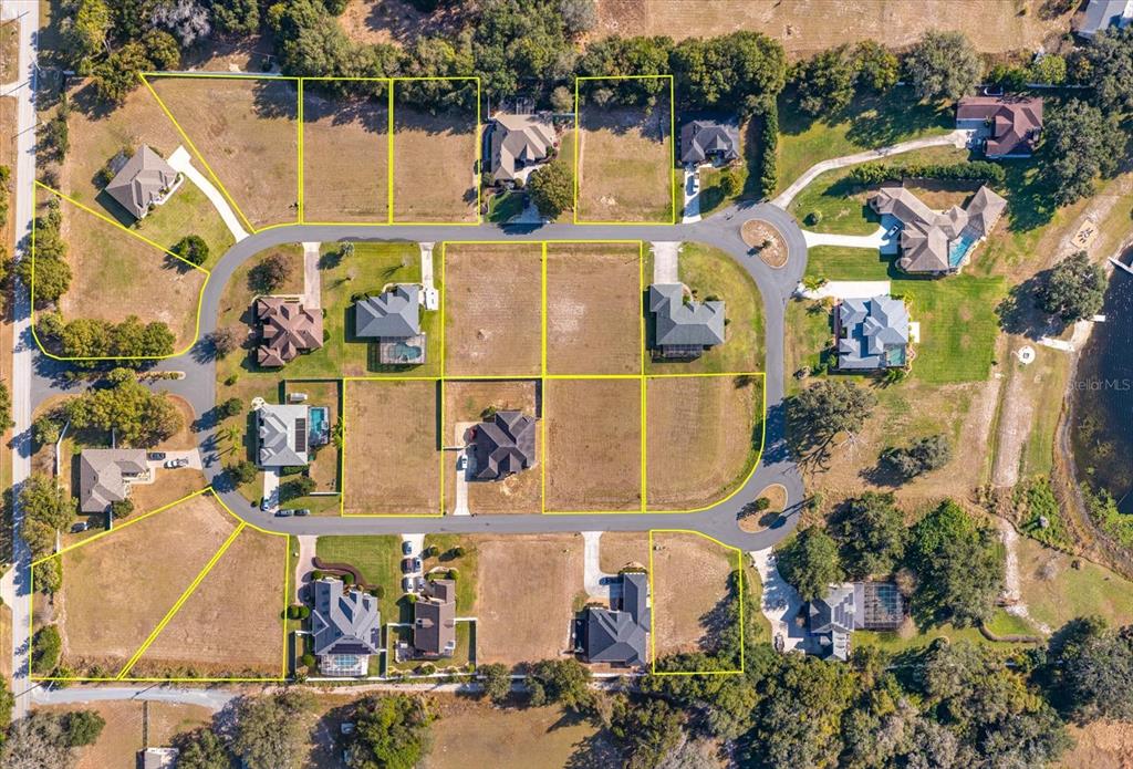 This aerial view shows a residential neighborhood with several houses and vacant lots — 1004 MYRTLE BREEZES COURT, FRUITLAND PARK, FL