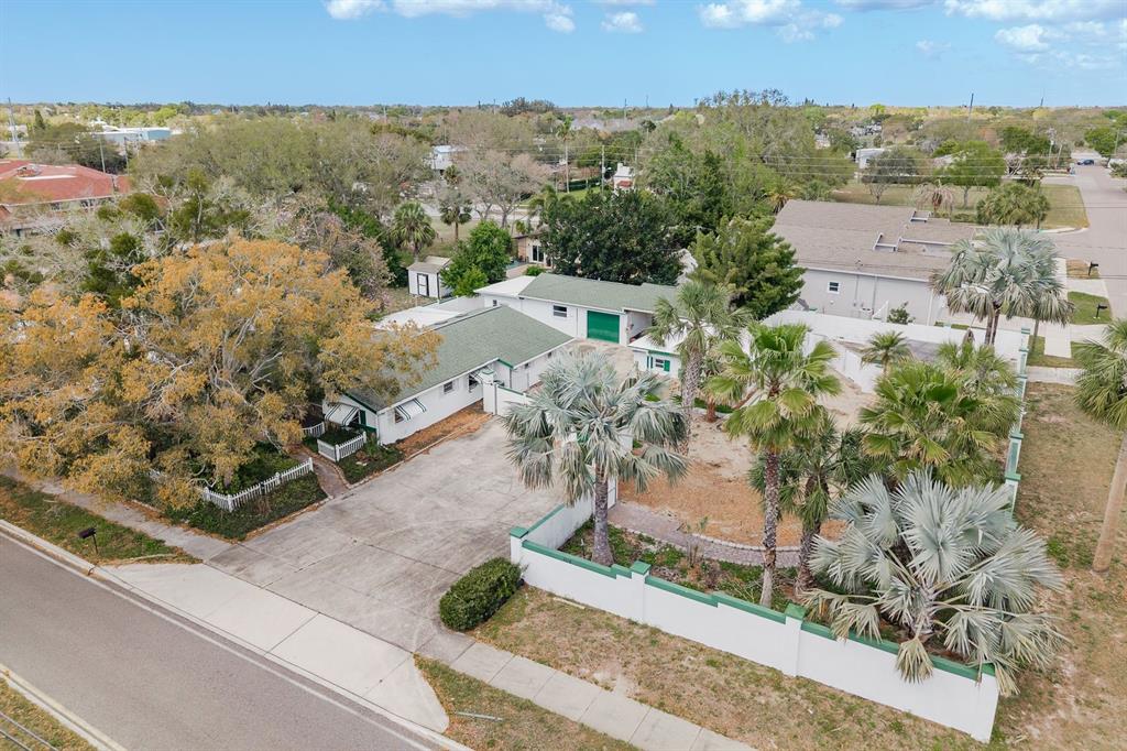 An aerial view shows a single-story house with a green roof, driveway, and walled yard — 1115 PENNSYLVANIA AVENUE, PALM HARBOR, FL