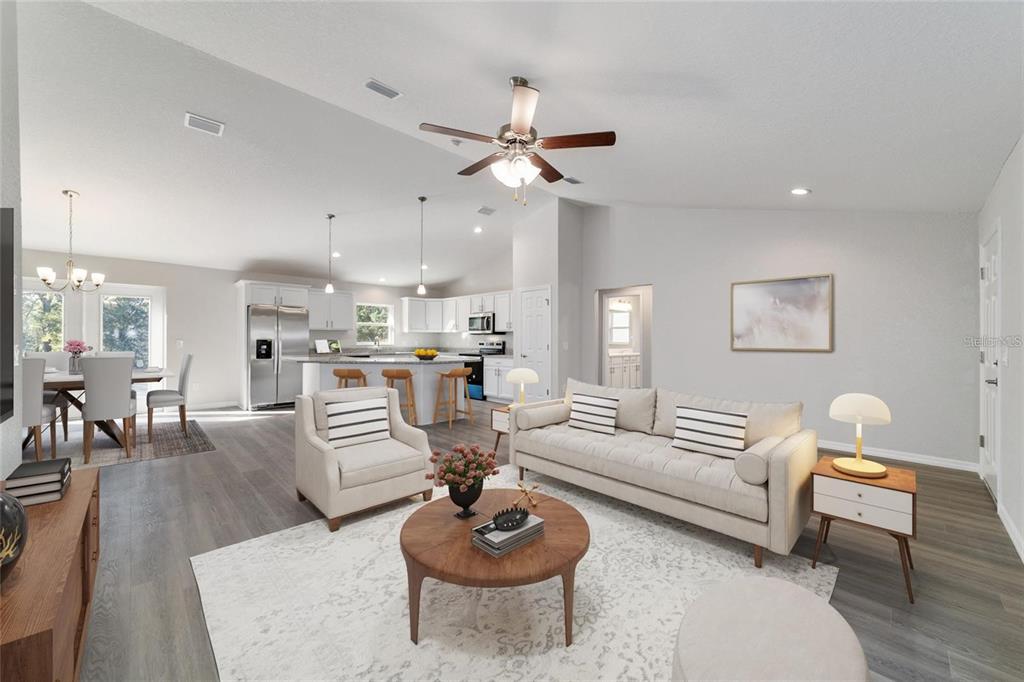 An open-concept living room and kitchen featuring light wood flooring and a vaulted ceiling — 6411 SW 204 AVENUE, DUNNELLON, FL