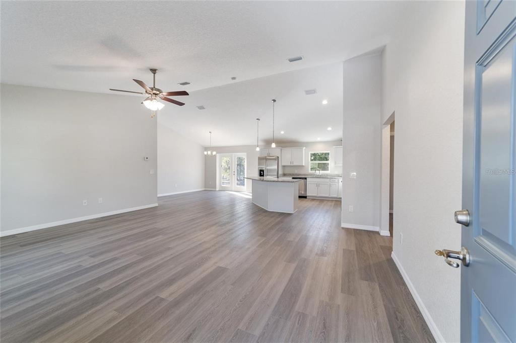 An open-concept living area with light gray walls, wood-look flooring, and a kitchen island — 6411 SW 204 AVENUE, DUNNELLON, FL