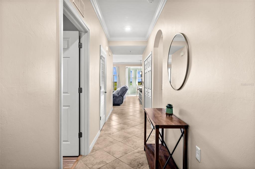 A hallway with tile flooring leads to an open living area with a view outside — 43020 GREENWAY BOULEVARD UNIT 312, PUNTA GORDA, FL