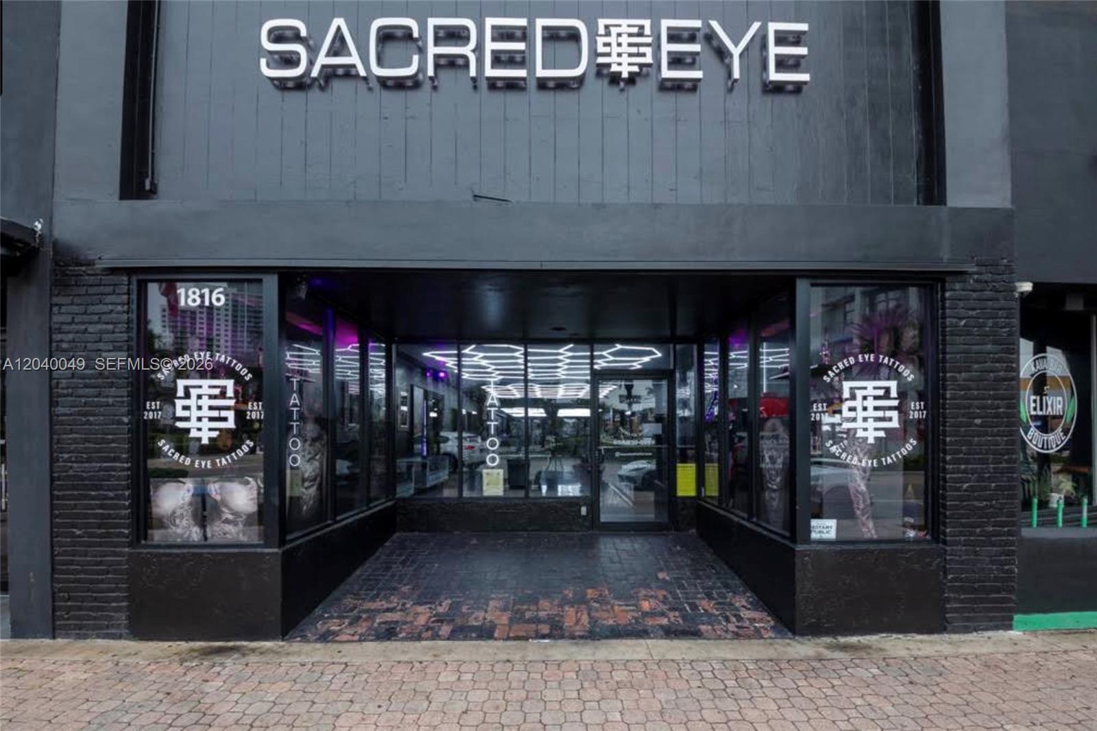 The exterior of a black brick building features a tattoo shop with large glass windows — 1816 Harrison St, Hollywood FL 33020, HOLLYWOOD, FL