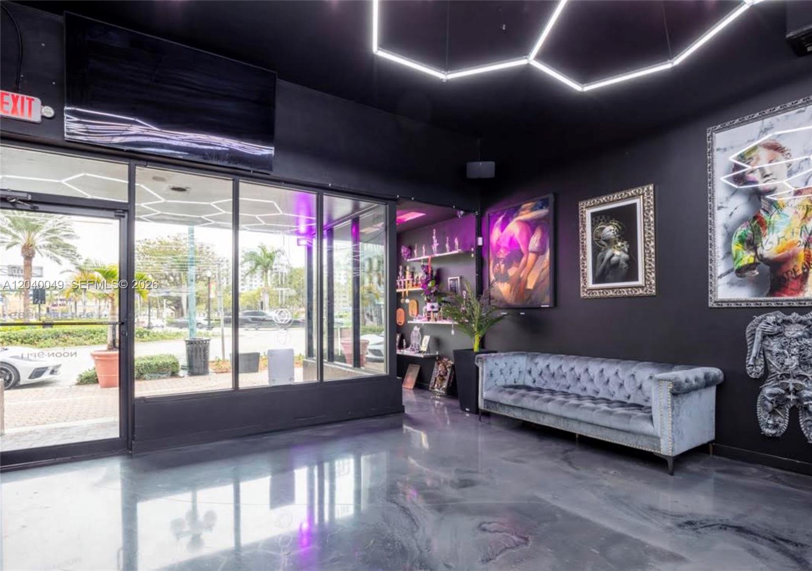 A modern waiting area features black walls, a grey tufted sofa, and hexagonal ceiling lights — 1816 Harrison St, Hollywood FL 33020, HOLLYWOOD, FL