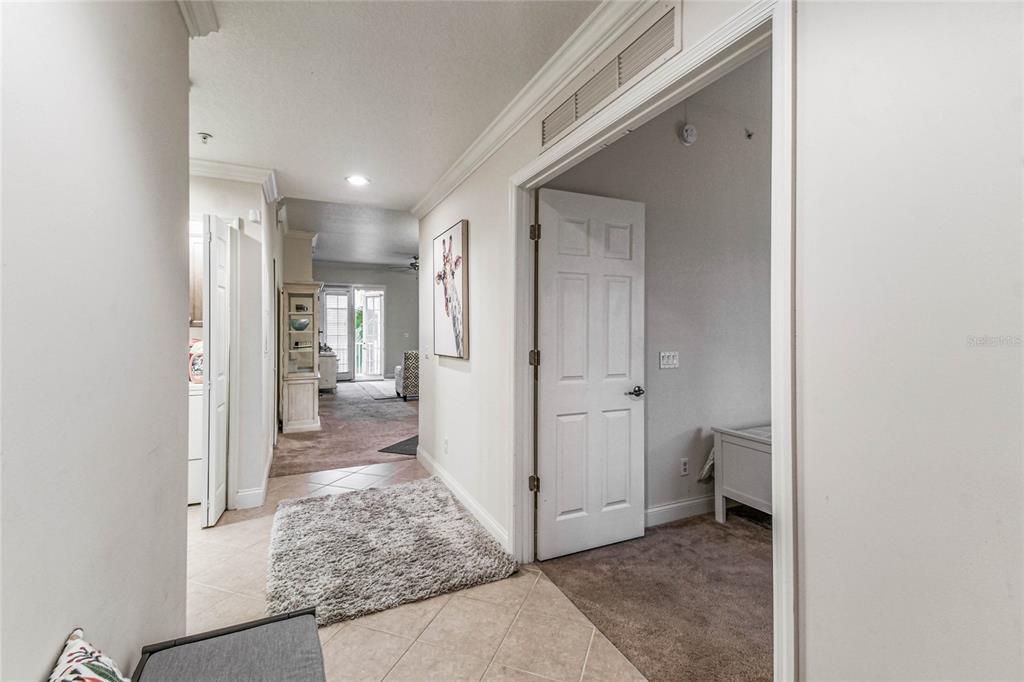 A hallway with tile flooring leads to a carpeted room and a living area beyond — 1501 NORTHERN HARRIER WAY UNIT 302, REUNION, FL