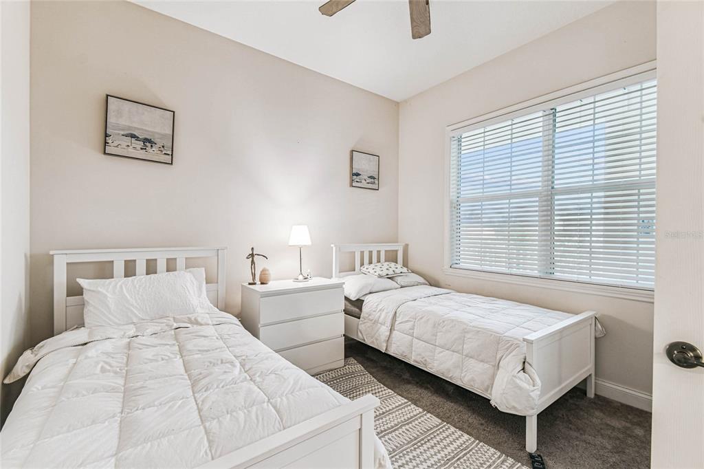 A bedroom features two white twin beds, a central nightstand, and a large window — 1501 NORTHERN HARRIER WAY UNIT 302, REUNION, FL