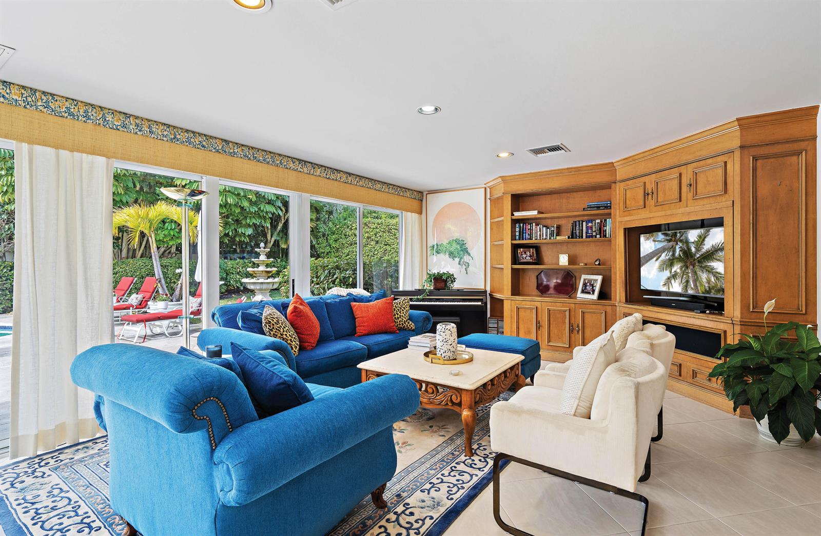 A living room features blue sofas, cream armchairs, a wooden entertainment center, and floor-to-ceiling windows — 11337 Lost Tree Way, North Palm Beach FL 33408, NORTH PALM BEACH, FL