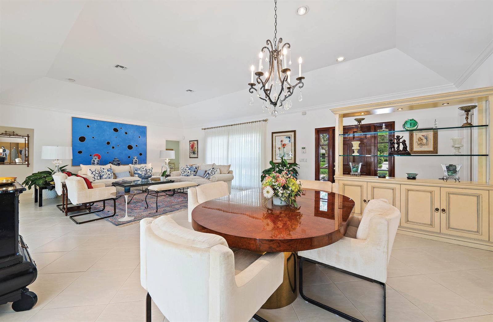 A bright, open-concept living and dining area features a large chandelier and tile flooring — 11337 Lost Tree Way, North Palm Beach FL 33408, NORTH PALM BEACH, FL