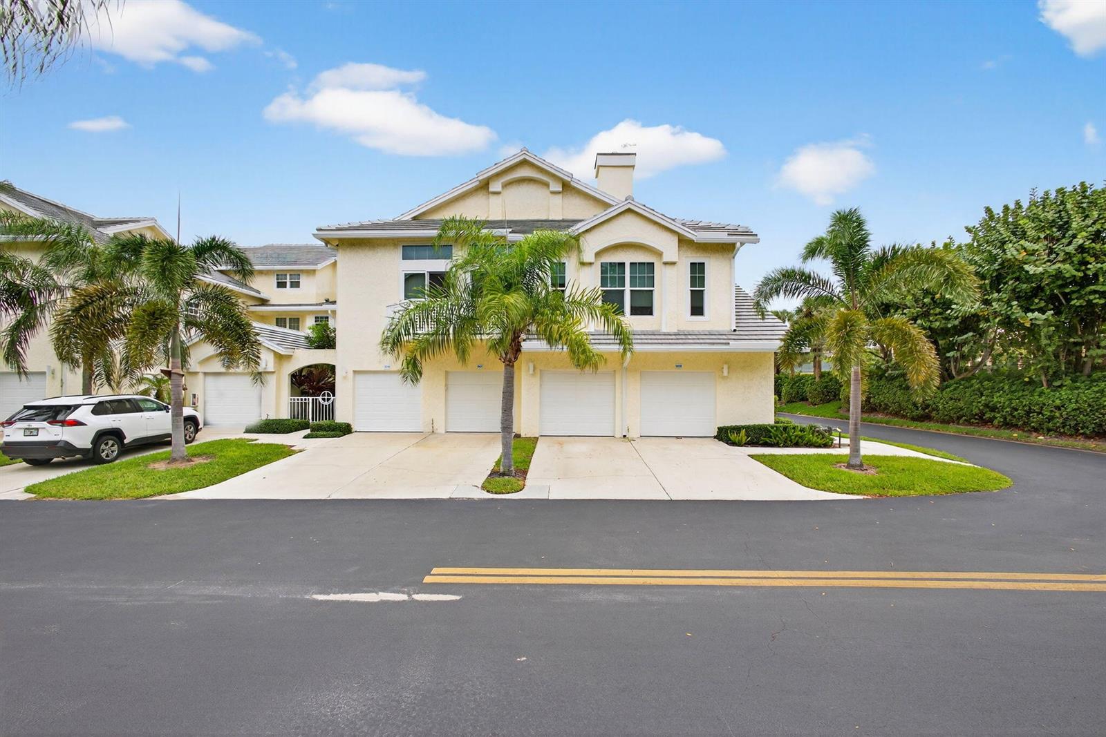 A multi-unit residential building features four garage doors, palm trees, and a paved driveway — 1609 Mizzenmast Way # 1609, Jupiter FL 33477, JUPITER, FL