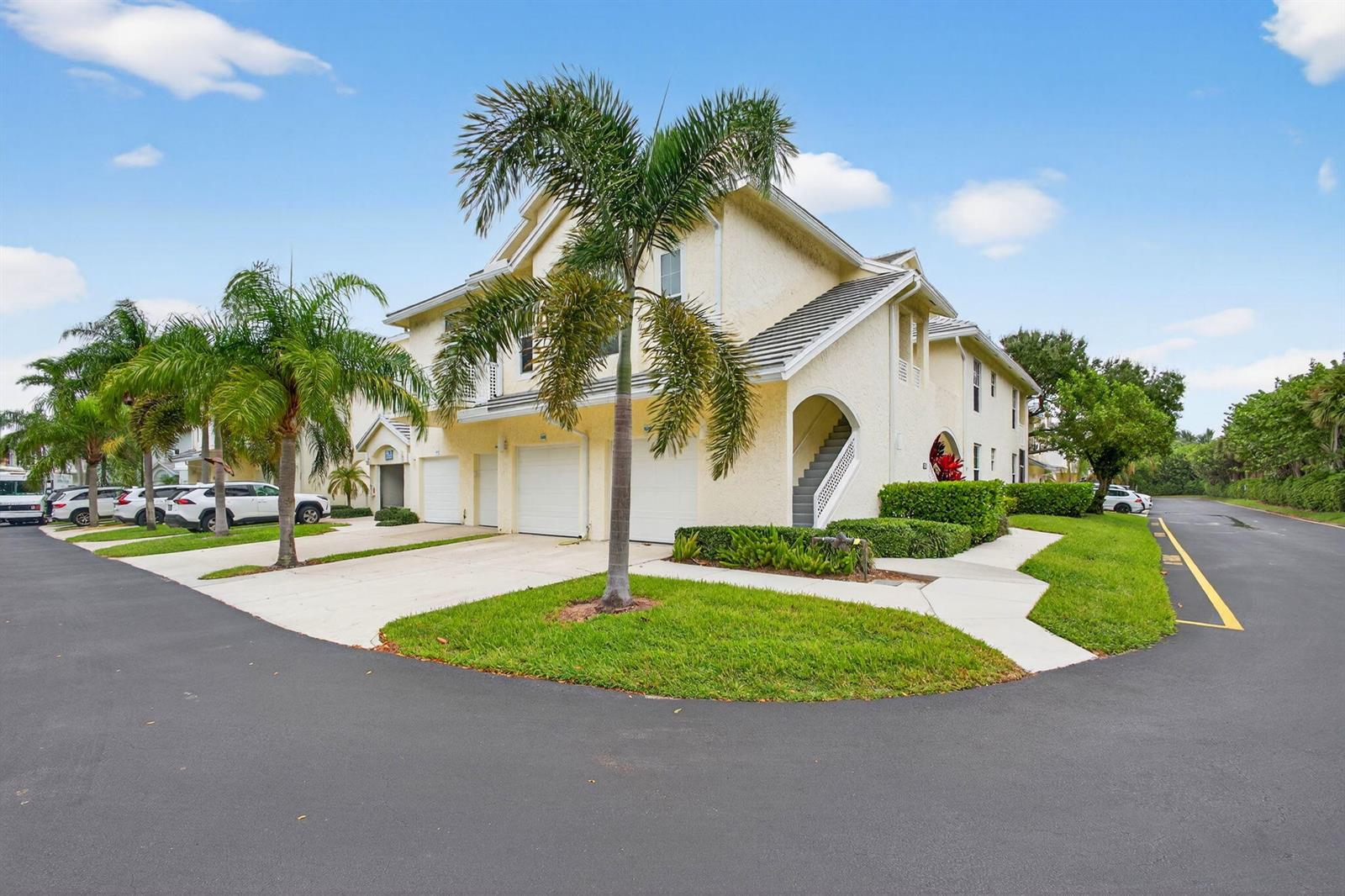 A two-story yellow stucco townhouse with a palm tree in the front yard — 1609 Mizzenmast Way # 1609, Jupiter FL 33477, JUPITER, FL