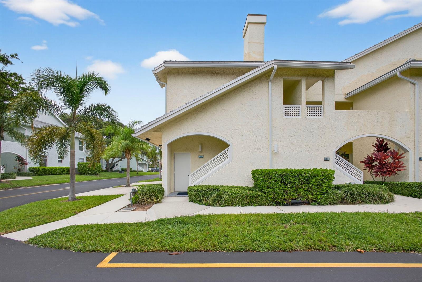 A two-story stucco townhouse with a chimney, arched entryways, and a palm tree in front — 1609 Mizzenmast Way # 1609, Jupiter FL 33477, JUPITER, FL