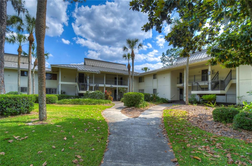 A concrete walkway leads to the entrance of a two-story apartment building with palm trees — 29300 BAY HOLLOW DRIVE UNIT 3258, WESLEY CHAPEL, FL