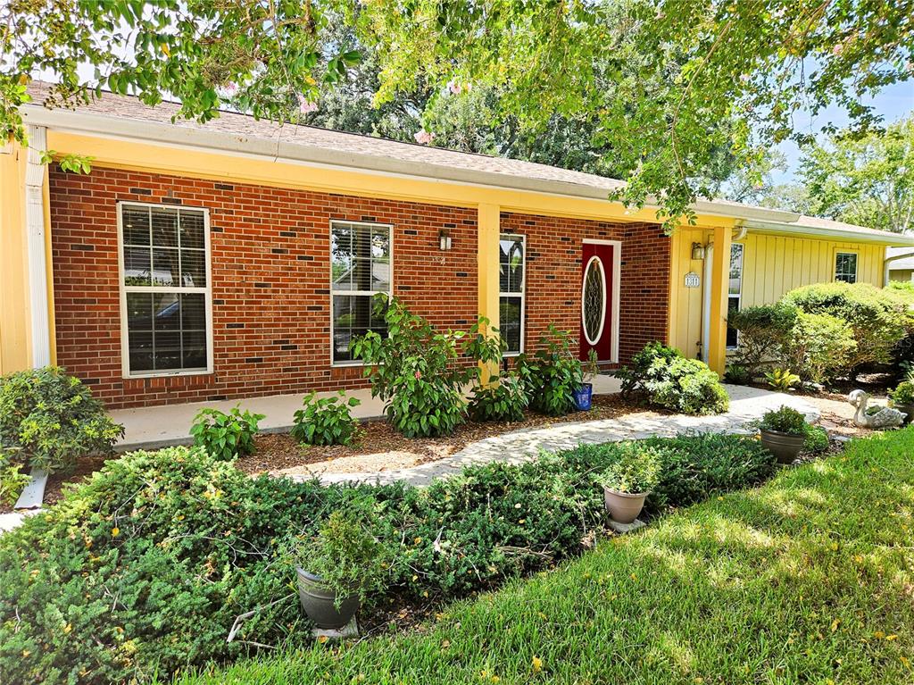 A single-story brick house with a yellow porch, front walkway, and landscaped yard — 1311 GLENVIEW LANE, LAKELAND, FL