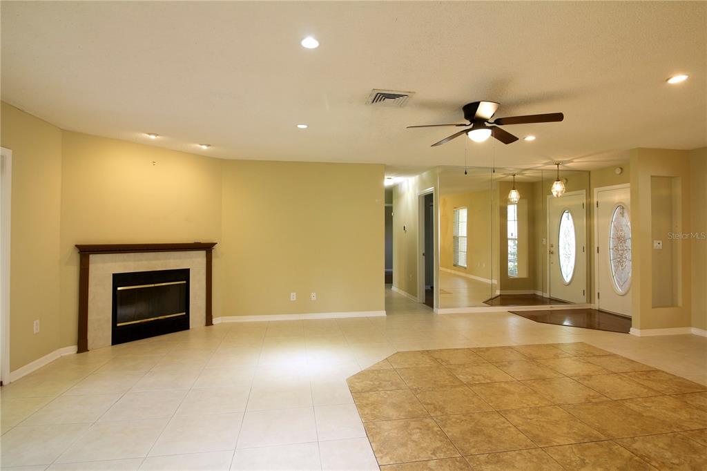 A living room features light tile flooring, a corner fireplace, and a mirrored entryway wall — 1311 GLENVIEW LANE, LAKELAND, FL