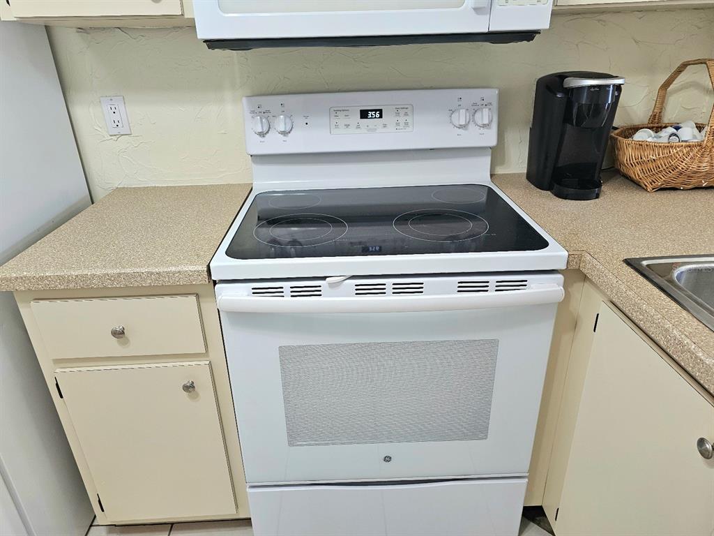 A white electric range sits between beige cabinets in a kitchen with laminate countertops — 25225 RAMPART BOULEVARD UNIT 1404, PUNTA GORDA, FL