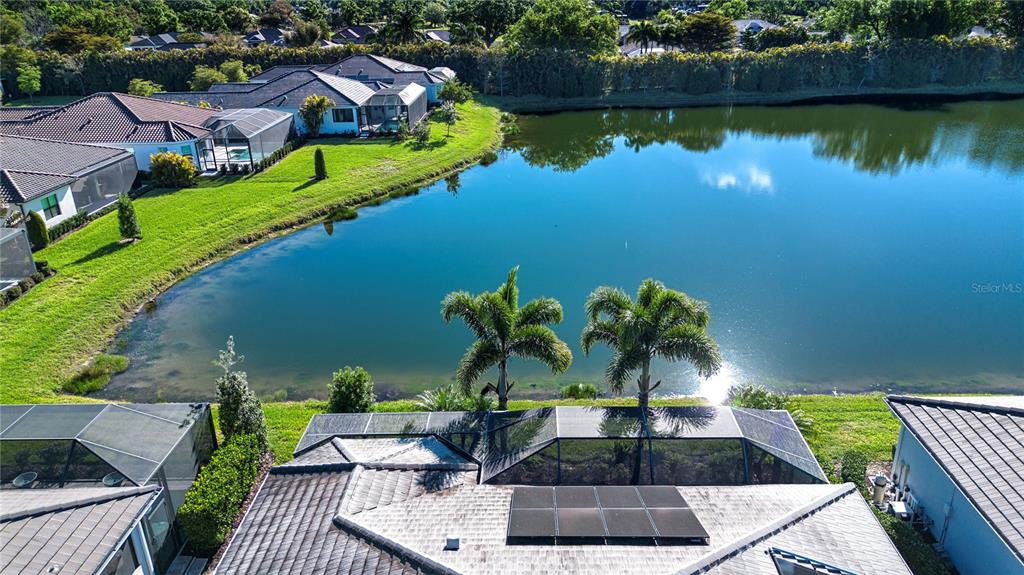 An aerial view shows a house with a screened pool enclosure overlooking a lake — 7732 SANDHILL LAKE DRIVE, SARASOTA, FL