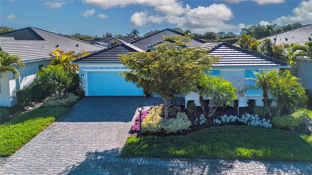 A single-story house with a blue garage door, a paved driveway, and landscaped front yard — 7732 SANDHILL LAKE DRIVE, SARASOTA, FL