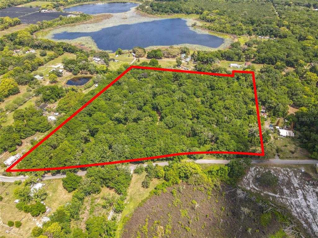 An aerial view shows a large, wooded plot of land outlined in red near a lake — 164 DENVER ROAD, CRESCENT CITY, FL