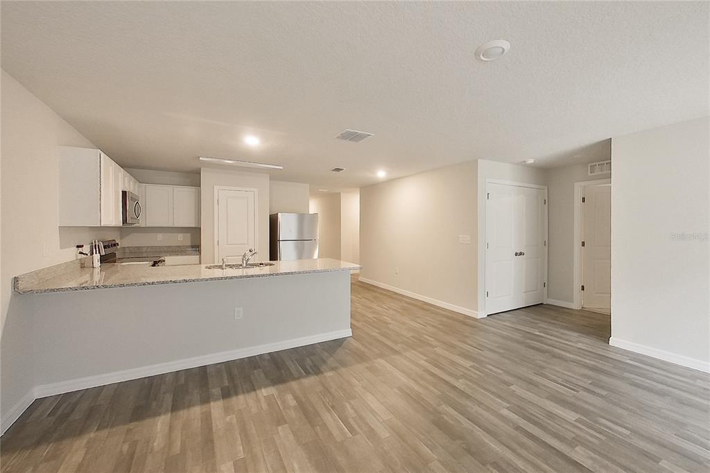 A kitchen with white cabinets and a granite island opens into a living area — 8755 N NOBLETON WAY, DUNNELLON, FL