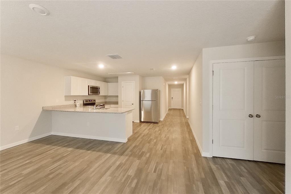 An open-concept kitchen features white cabinets, stainless steel appliances, and light-colored countertops — 8755 N NOBLETON WAY, DUNNELLON, FL