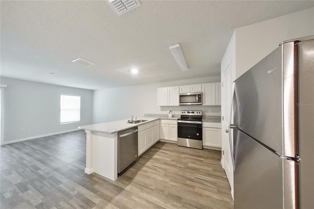 A kitchen with white cabinets, stainless steel appliances, and a granite-topped island — 8755 N NOBLETON WAY, DUNNELLON, FL