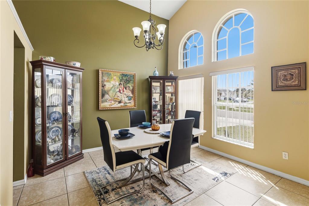 A dining room with a white table, black chairs, two display cabinets, and arched windows — 265 KASSIK CIRCLE, ORLANDO, FL
