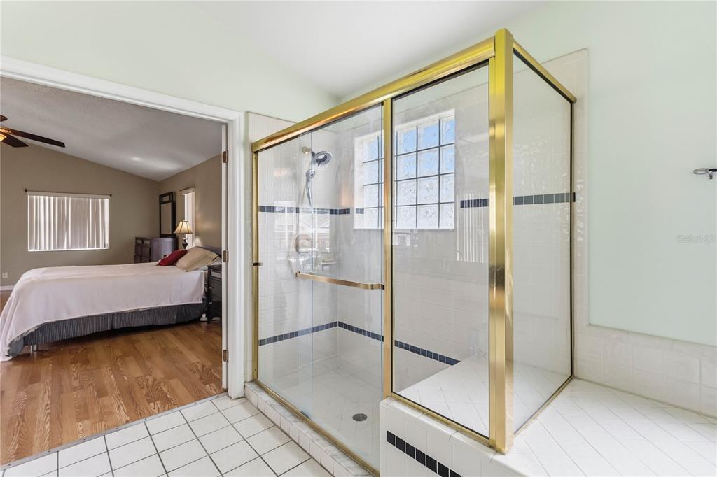 A bathroom with a glass-enclosed shower featuring gold trim and white tile flooring — 265 KASSIK CIRCLE, ORLANDO, FL