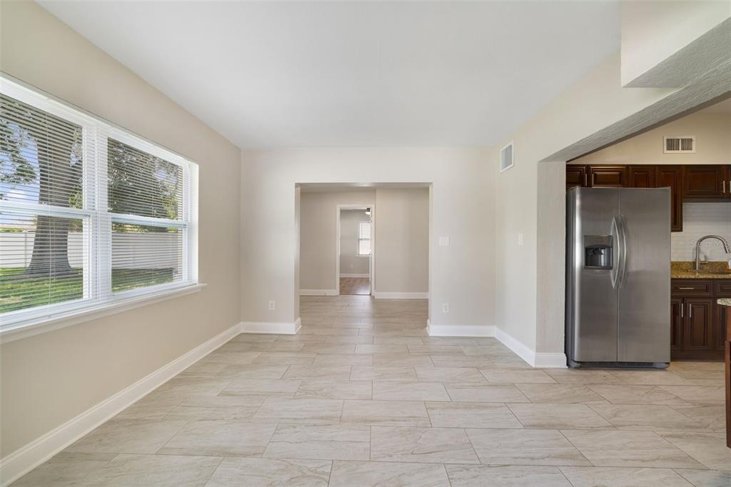 A dining area with tile flooring, a window, and an adjacent kitchen with stainless appliances — 1117 NEUSE AVENUE, ORLANDO, FL