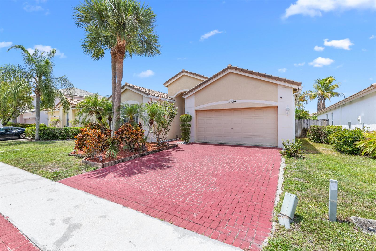 A single-story house features a red brick driveway, a two-car garage, and palm trees — 10720 Oak Bend Way, Wellington FL 33414, WELLINGTON, FL
