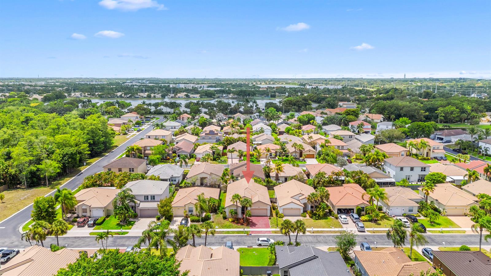 An aerial view shows a suburban neighborhood with single-family homes, palm trees, and a lake — 10720 Oak Bend Way, Wellington FL 33414, WELLINGTON, FL