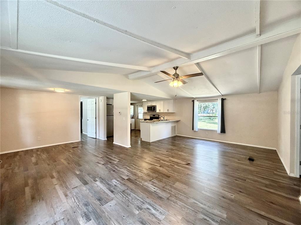 A single-story manufactured home with a covered front porch sits on a grassy, tree-filled lot — 6655 NW 49TH COURT, OCALA, FL