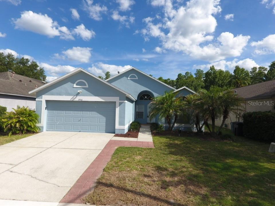 A blue single-story house with a two-car garage and a paved walkway — 19310 WEEDON COURT, LAND O LAKES, FL