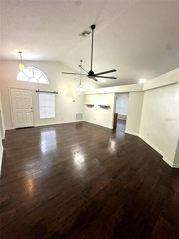 A spacious living room features dark wood flooring, a vaulted ceiling, and a ceiling fan — 19310 WEEDON COURT, LAND O LAKES, FL
