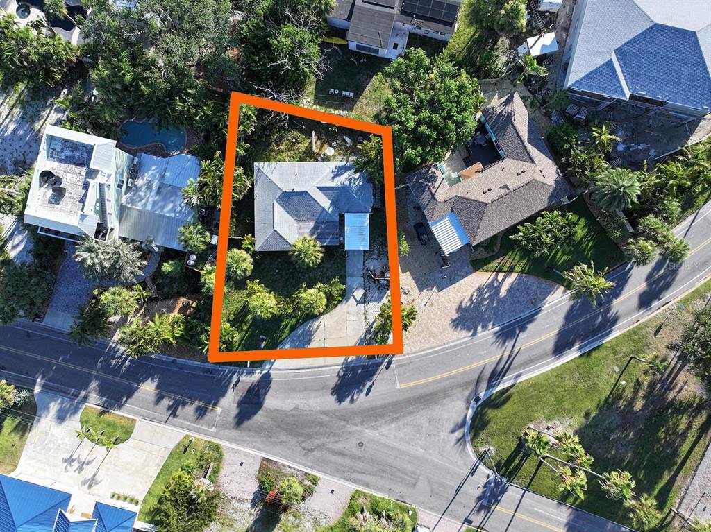 An aerial view shows a single-story house with a driveway on a landscaped lot — 3929 BELLE VISTA DRIVE, ST PETE BEACH, FL