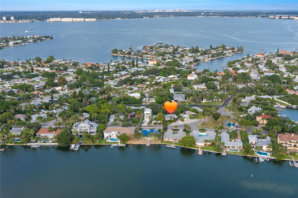 An aerial view shows a waterfront residential neighborhood with a heart icon marking a house — 3929 BELLE VISTA DRIVE, ST PETE BEACH, FL
