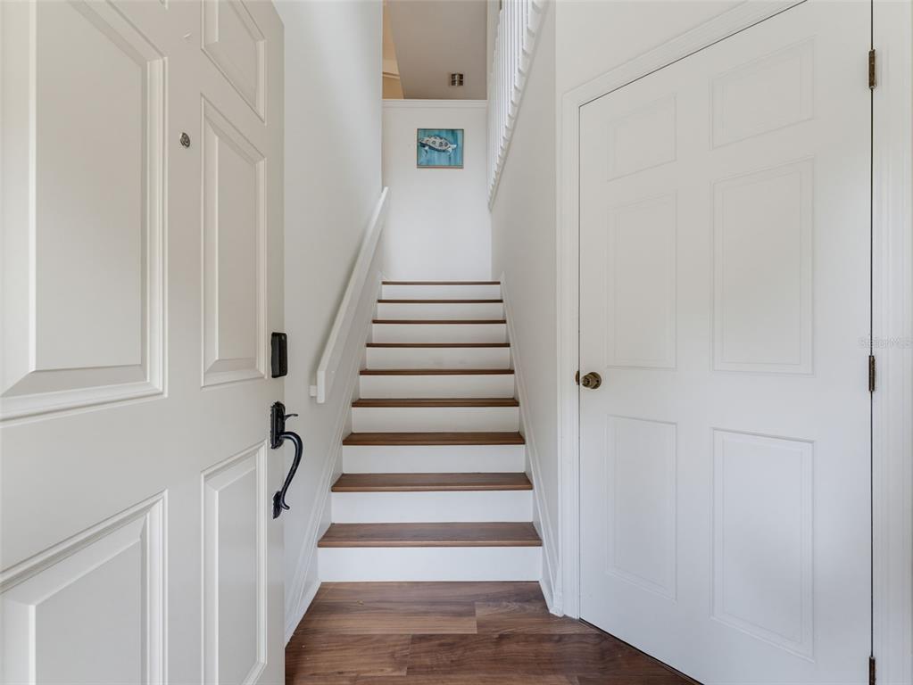 An entryway features a staircase with wood treads, white risers, and a white handrail — 1491 MAHOGANY LANE UNIT 1491, PALM HARBOR, FL