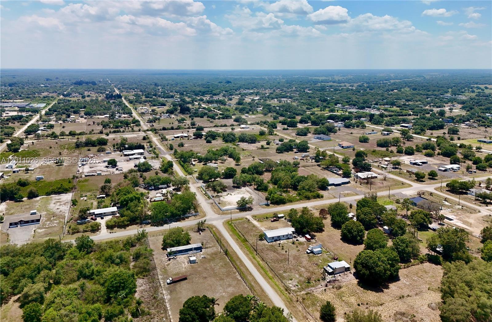 An aerial view shows a rural residential area with scattered houses, trees, and dirt roads — 242 BALD CYPRESS AVE, Clewiston FL 33440, CLEWISTON, FL