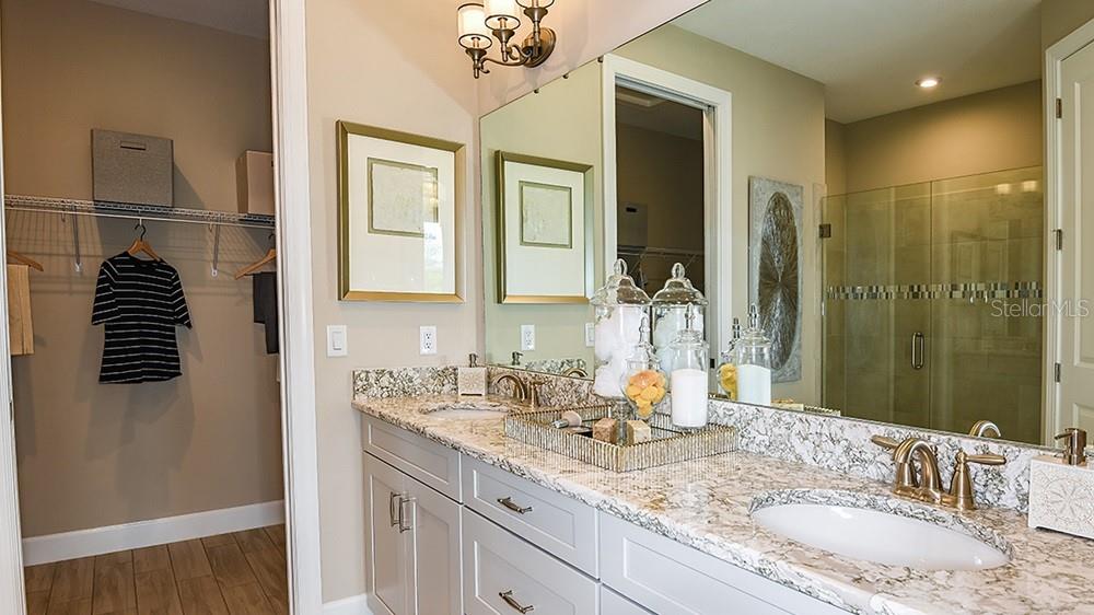 A bathroom features a double vanity with granite countertops, a large mirror, and an adjacent closet — 14525 DERNA TERRACE, BRADENTON, FL