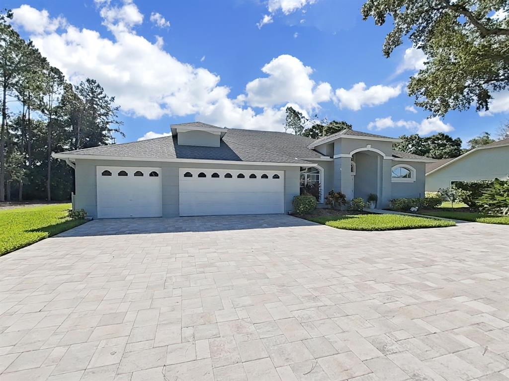 A single-story house with a gray exterior, a three-car garage, and a paved driveway — 17110 DOWNS DRIVE, ODESSA, FL