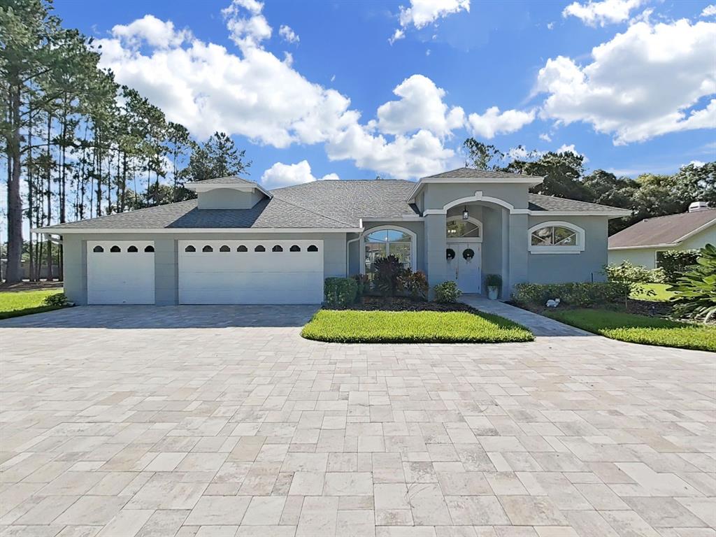 A single-story house with a gray exterior, a three-car garage, and a paved driveway — 17110 DOWNS DRIVE, ODESSA, FL