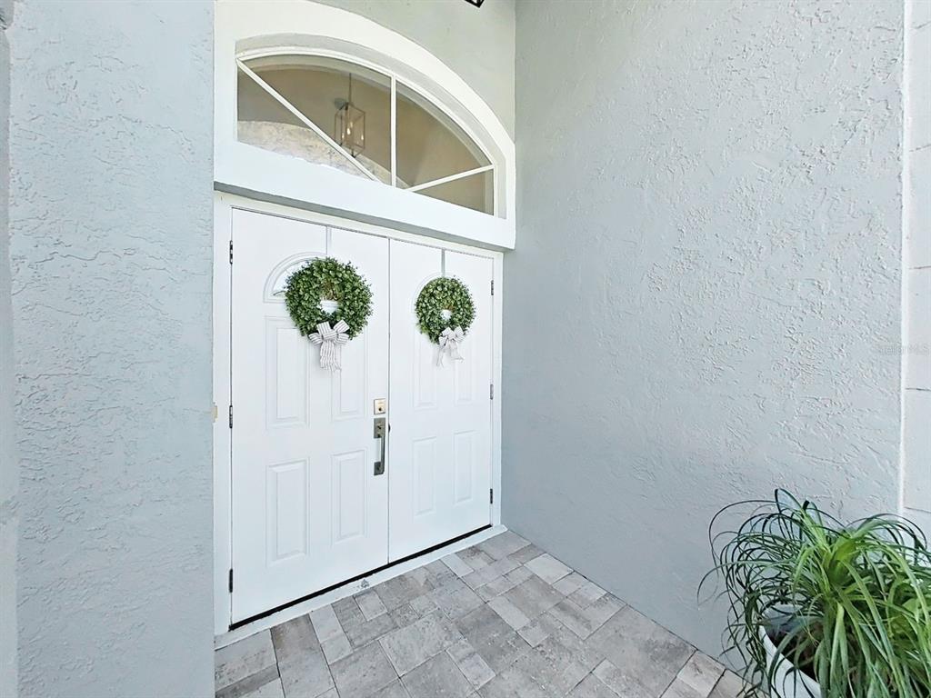 A white double front door with wreaths sits under an arched transom window — 17110 DOWNS DRIVE, ODESSA, FL