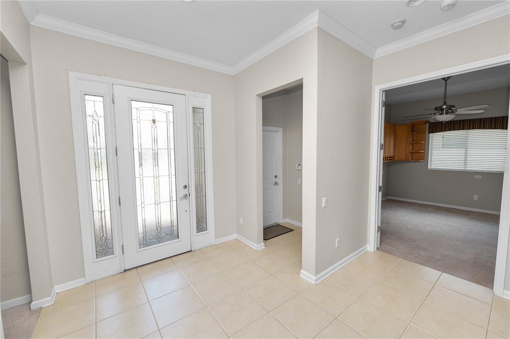 An entryway with tile flooring, a glass-paneled front door, and an adjacent room with carpet — 500 ARENA DRIVE, DAVENPORT, FL