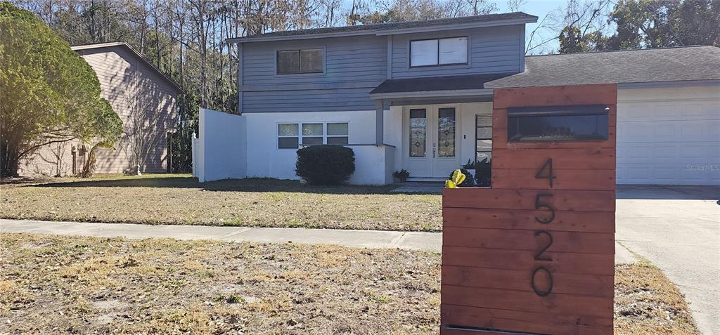 A two-story house with a wooden mailbox post in the foreground and a white garage — 4520 GRAINARY AVENUE, TAMPA, FL