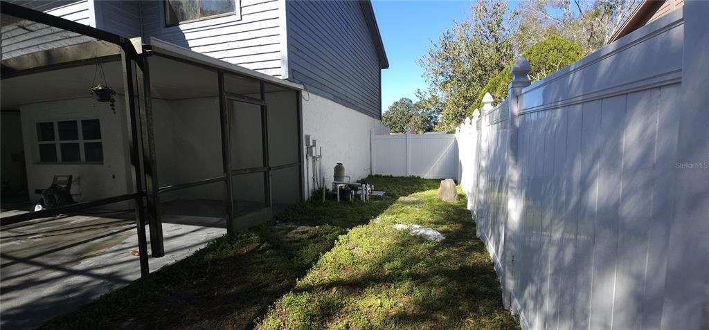 A side yard features a screened-in patio, a white vinyl fence, and pool equipment — 4520 GRAINARY AVENUE, TAMPA, FL