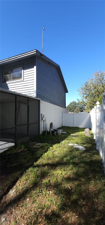A side view of a house exterior showing a screened-in porch and a grassy yard — 4520 GRAINARY AVENUE, TAMPA, FL
