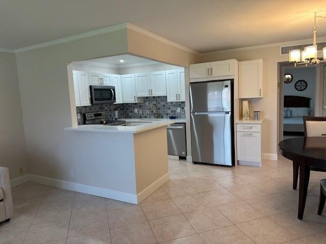 A kitchen with white cabinets, stainless steel appliances, and tile flooring opens to a dining area — 251 Seville K # 251, Delray Beach FL 33446, DELRAY BEACH, FL